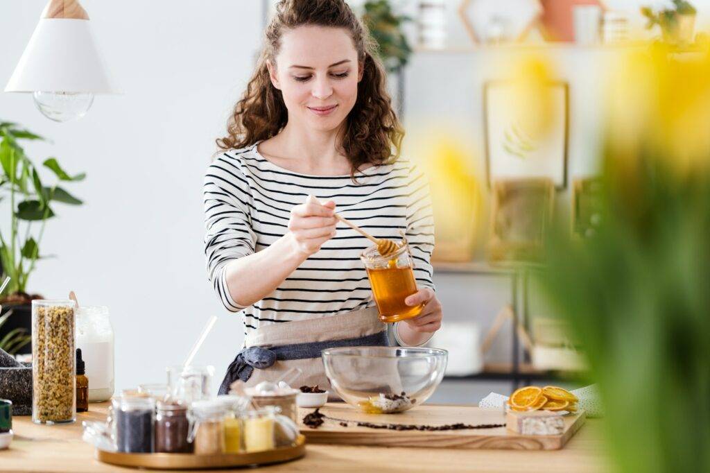 Smiling woman pouring honey