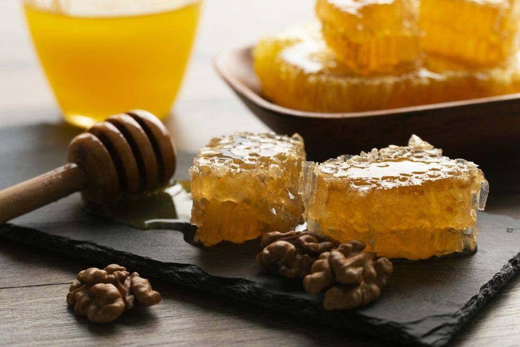 Honeycomb on slate tray with honey and nuts on kitchen table